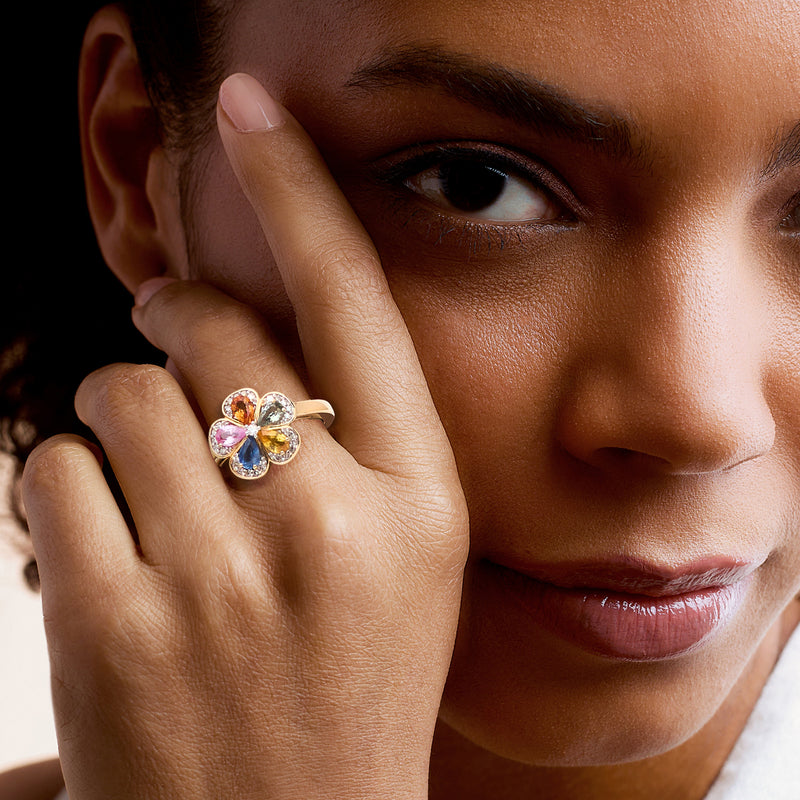 14kt yellow gold flower ring with multicolored sapphires and diamond accents on hand