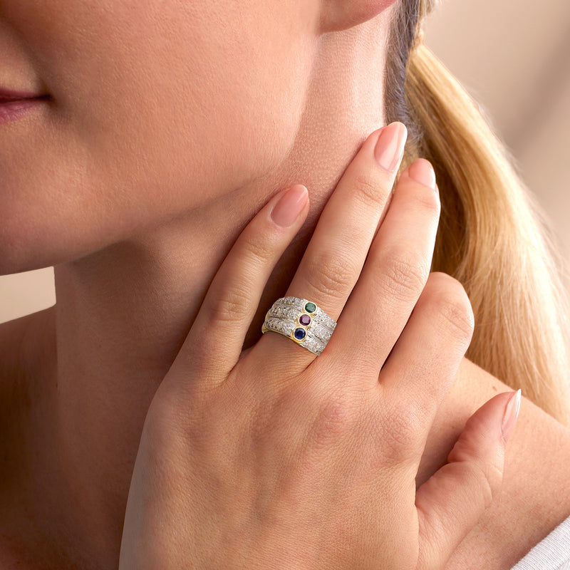 Multi-gemstone ring on finger with blue, pink, and green stones in yellow gold
