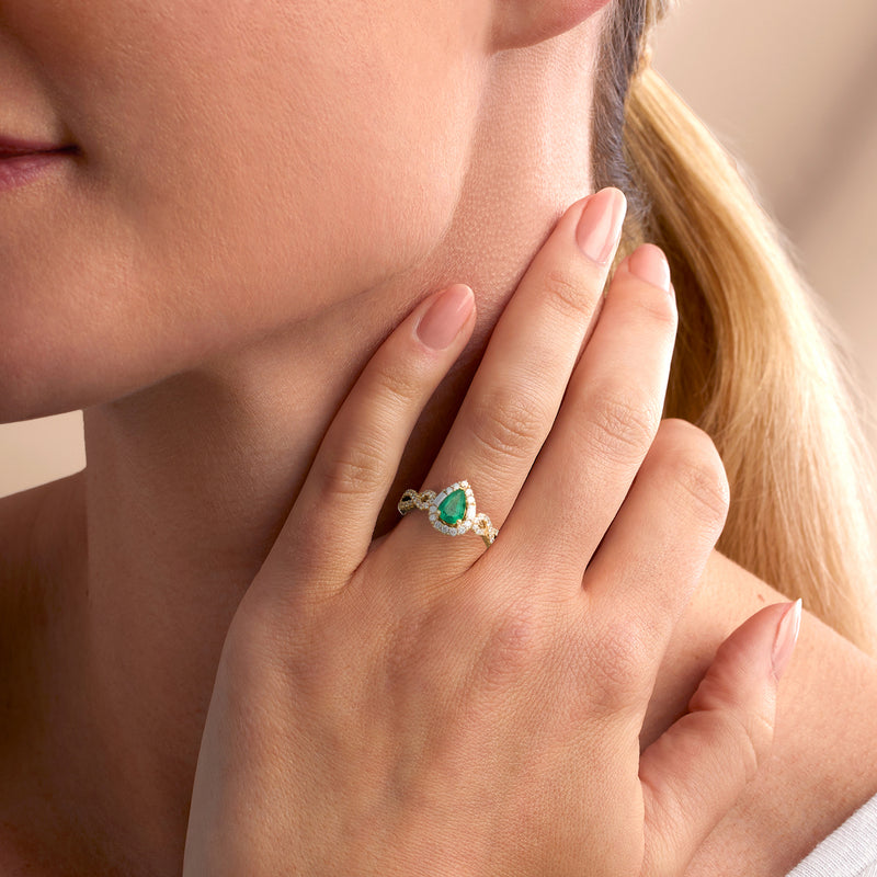 Emerald pear and diamond halo ring in 14kt yellow gold worn on hand