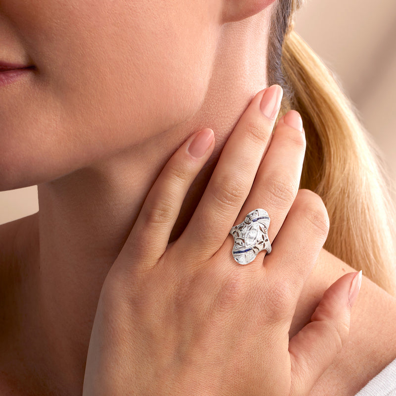 Vintage white gold ring with blue sapphire and diamond-look stones worn on hand, close-up