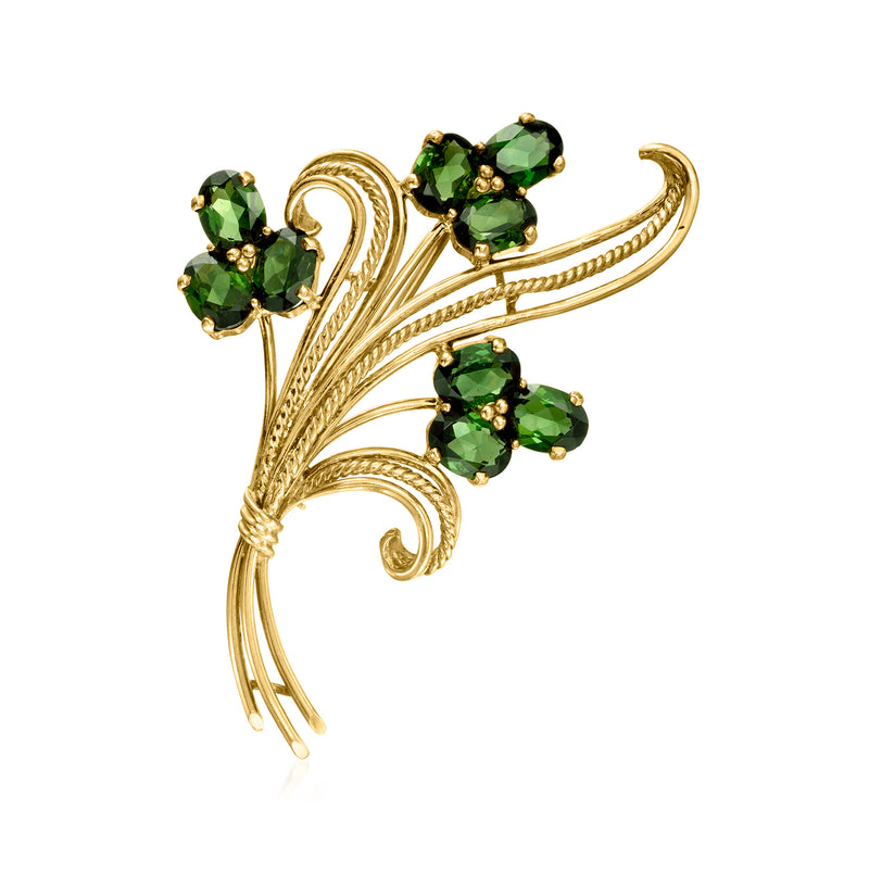 14kt yellow gold flower pin with four green gemstones on a swirling vine design
