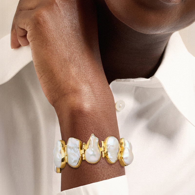 Baroque pearl bracelet worn on wrist with white iridescent pearls and gold links