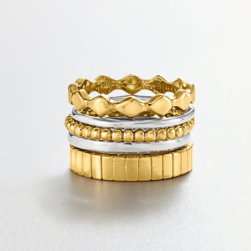 Five stackable rings in gold and silver with wavy, beaded, and ribbed finishes
