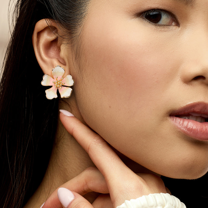 Gold-plated white enamel flower stud earring with pink center on model