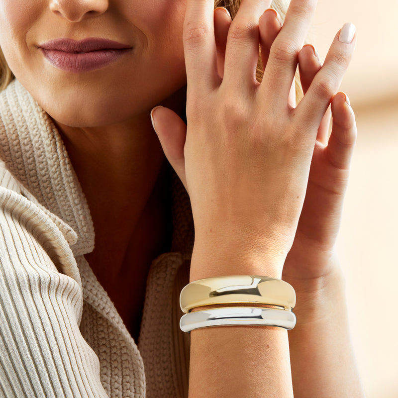 Two-tone cuff bracelet on wrist: gold-plated top band and silver inner band