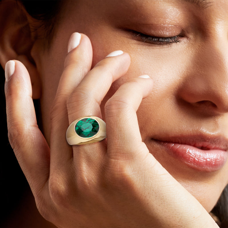 Yellow gold-plated oval ring with simulated emerald green gemstone on hand