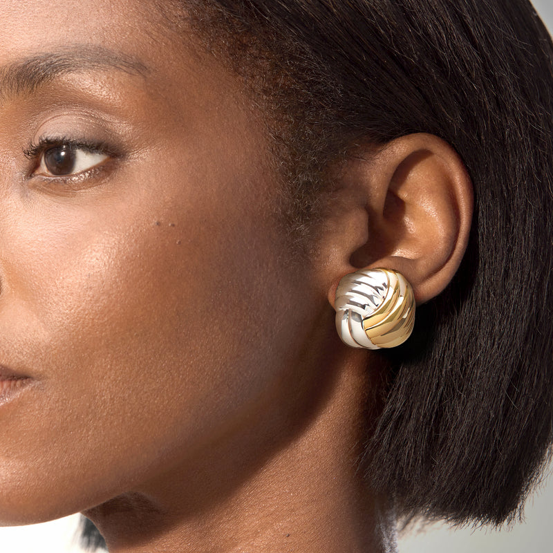 Close-up twisted square stud earring in silver and gold-plated ridged swirl on ear