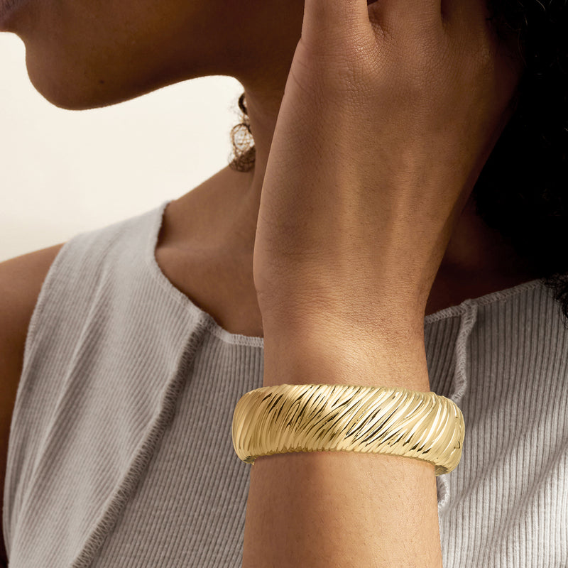 Yellow gold-plated textured bangle bracelet on wrist, ridged twisted pattern