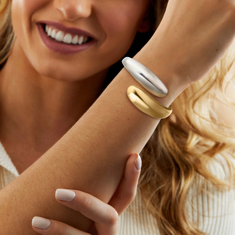 Two-tone cuff bracelet on wrist, smooth silver and gold-plated curved design