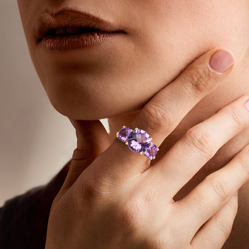 Amethyst three-stone ring on hand, oval center with two smaller oval side stones