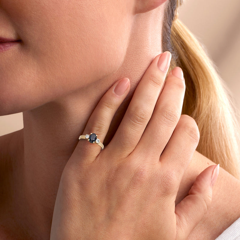 Vintage sapphire and diamond ring on finger, 14kt yellow gold band with oval center stone
