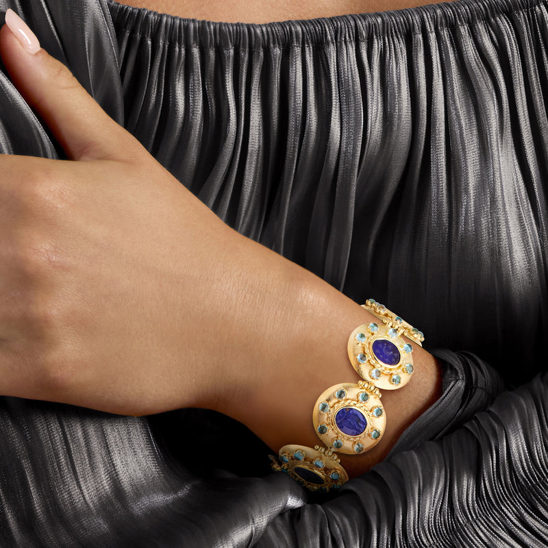 Gold-tone bracelet on wrist with two blue oval glass cabochons and light blue stones