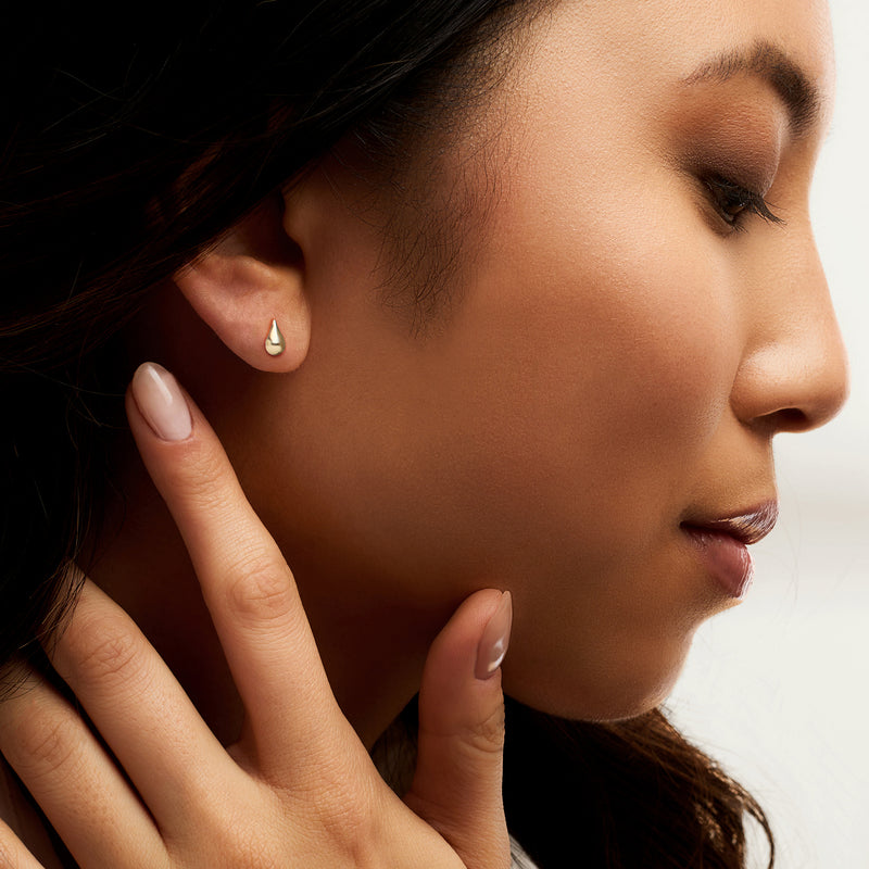 Petite yellow gold teardrop stud earrings worn, polished drop studs