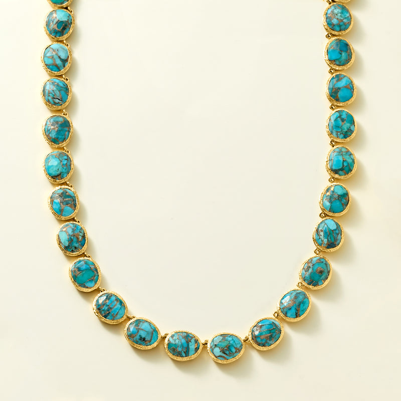 Gold necklace with evenly spaced oval turquoise cabochon stones along chain