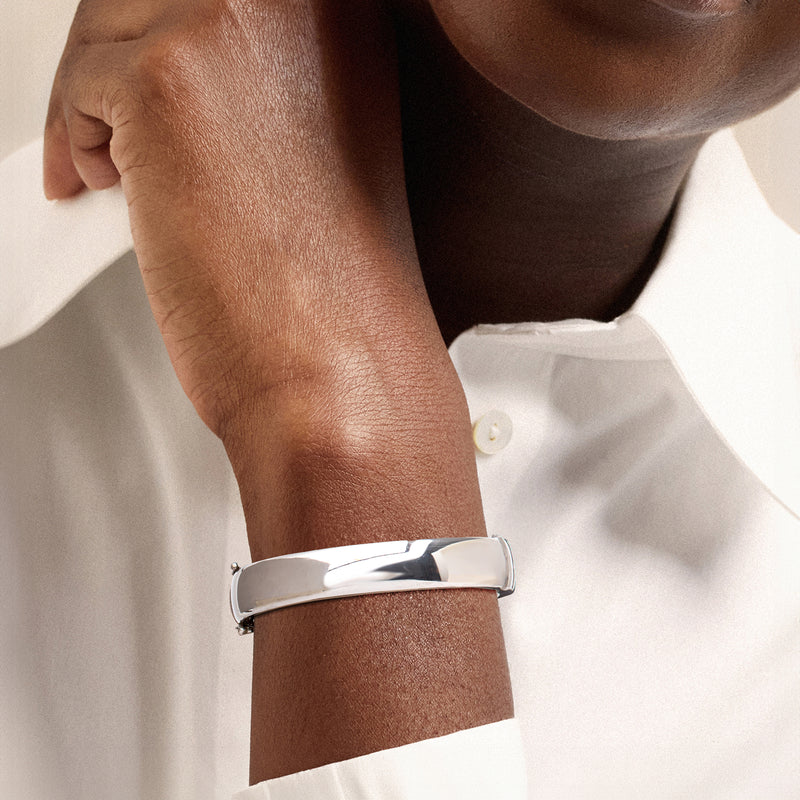 Polished rhodium-plated bangle on wrist, smooth rounded silver cuff