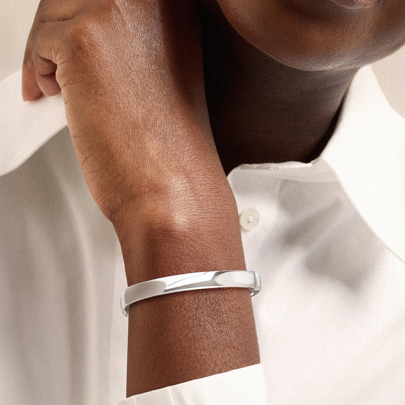 Rhodium-plated bangle bracelet worn on wrist, smooth 8mm silver cuff