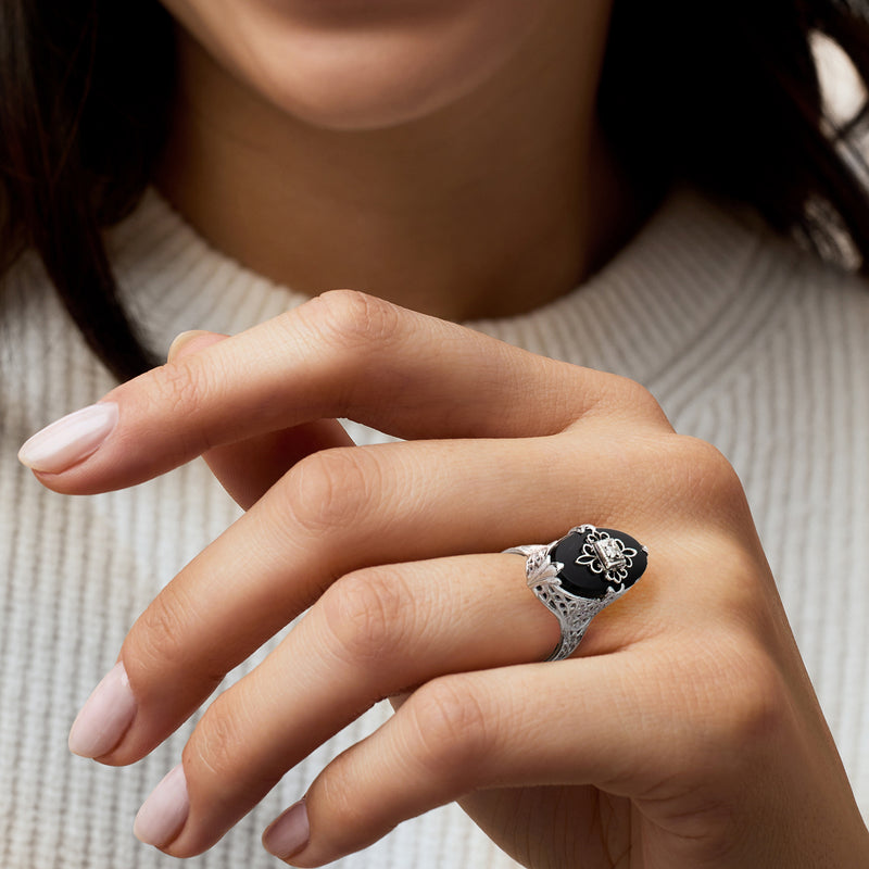 Onyx cabochon ring on hand with black oval stone and intricate flower diamond detail