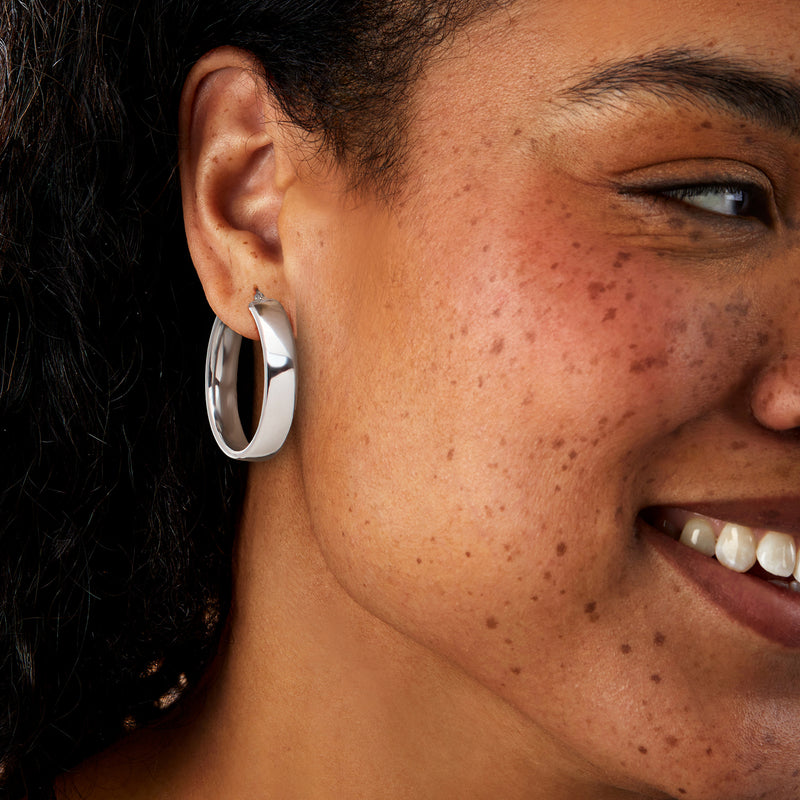 Rhodium-plated hoop earrings on ear, small round silver hoops in side view