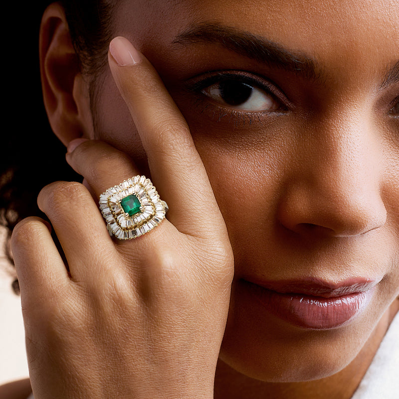 Emerald and diamond halo ring on hand, 14k yellow gold with green center stone