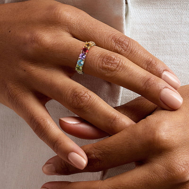 Multi-gemstone ring on hand, gold band with small colorful stones