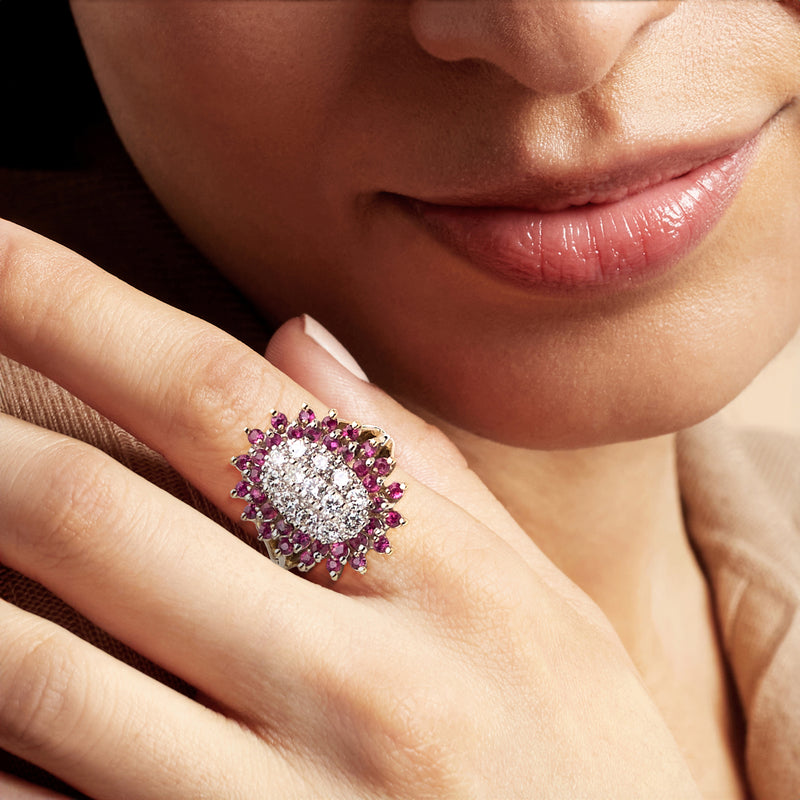 Ruby and diamond cluster ring on finger, set in 14kt yellow gold