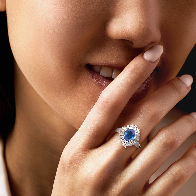 Sapphire and diamond cocktail ring on finger, oval blue center with round halo