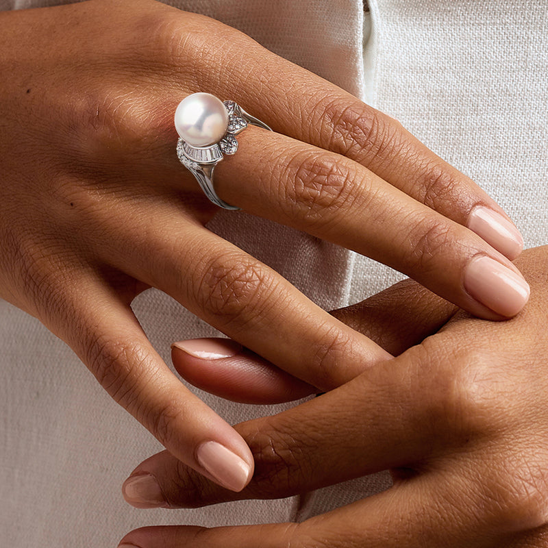 Pearl and diamond ring on hand, round cultured pearl with sparkling side stones in white gold