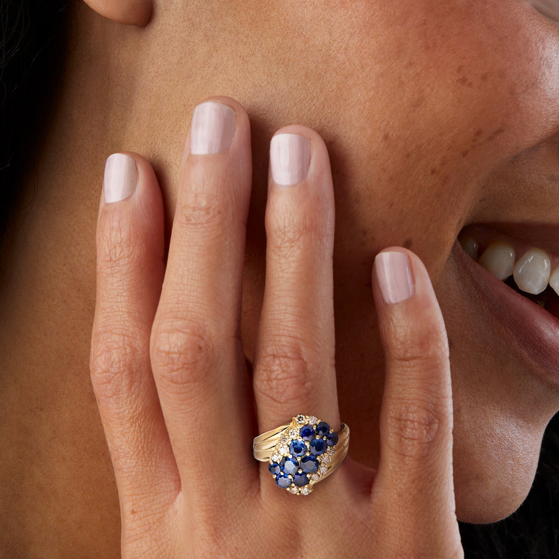 Yellow gold sapphire and diamond cluster ring on hand