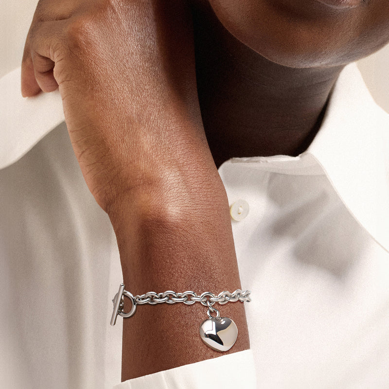 Rhodium-plated puff heart toggle bracelet worn on wrist, curb chain with heart charm
