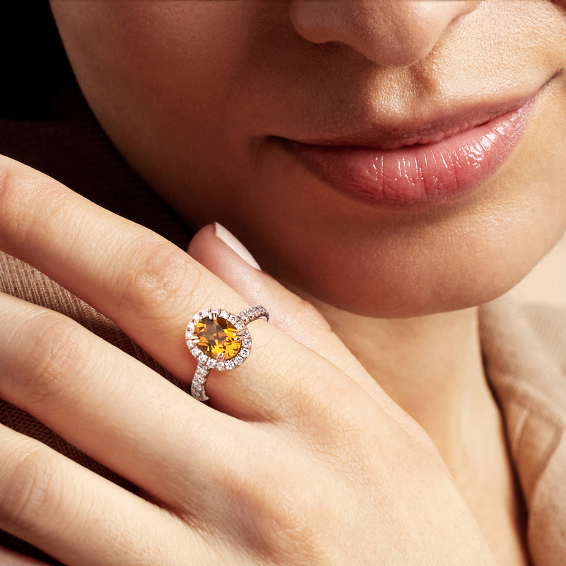 Rose gold citrine diamond ring worn on finger, round halo gemstone close-up
