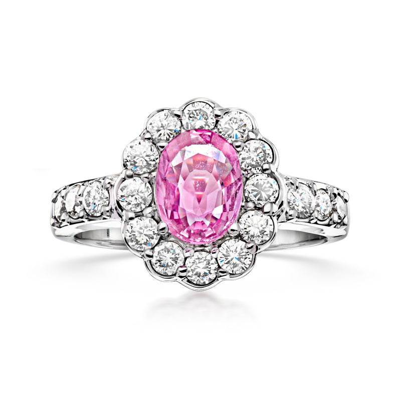 Vintage pink sapphire oval center ring with diamond halo and white gold band.