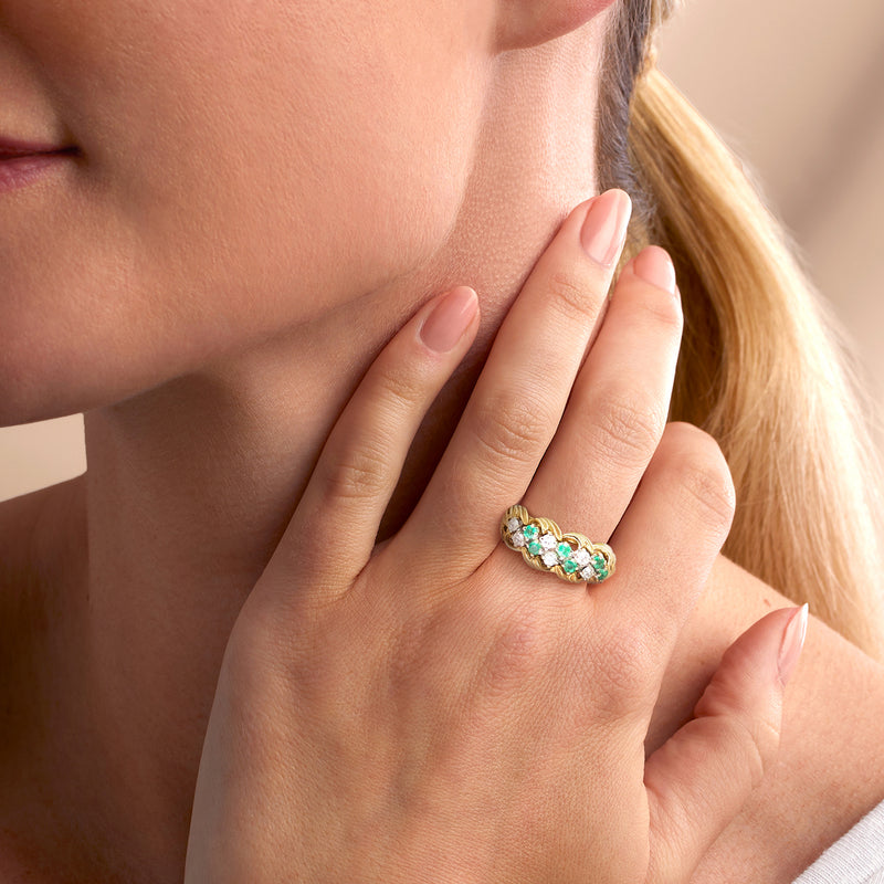 Twisted 18kt yellow gold ring with green emeralds and diamonds on hand