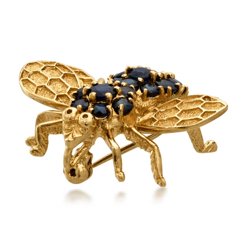 Yellow gold bee pin with dark blue sapphire cluster body and faceted wing details