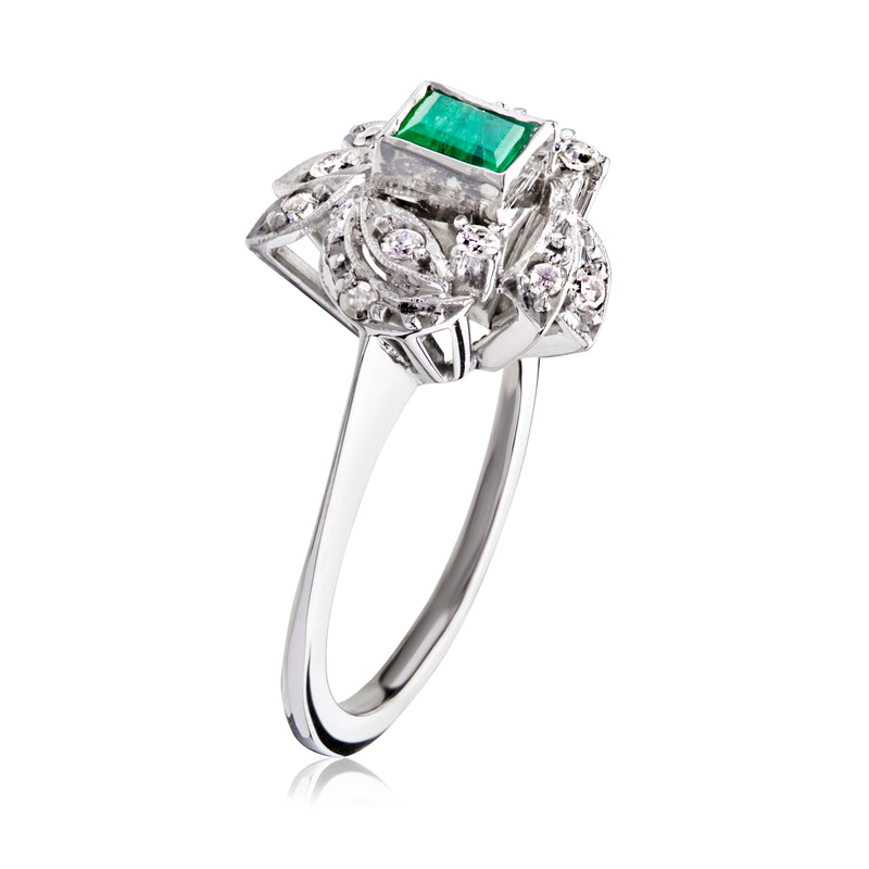 Side view of emerald and diamond ring with green center stone in ornate prongs
