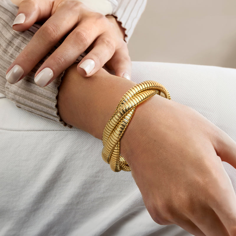 Gold-plated three-strand twisted bracelet on wrist, yellow gold tone coils