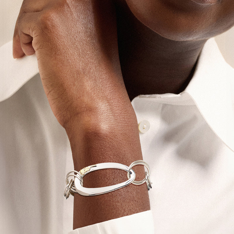 Sterling silver link bracelet with oval rings and hinged bar, worn on wrist