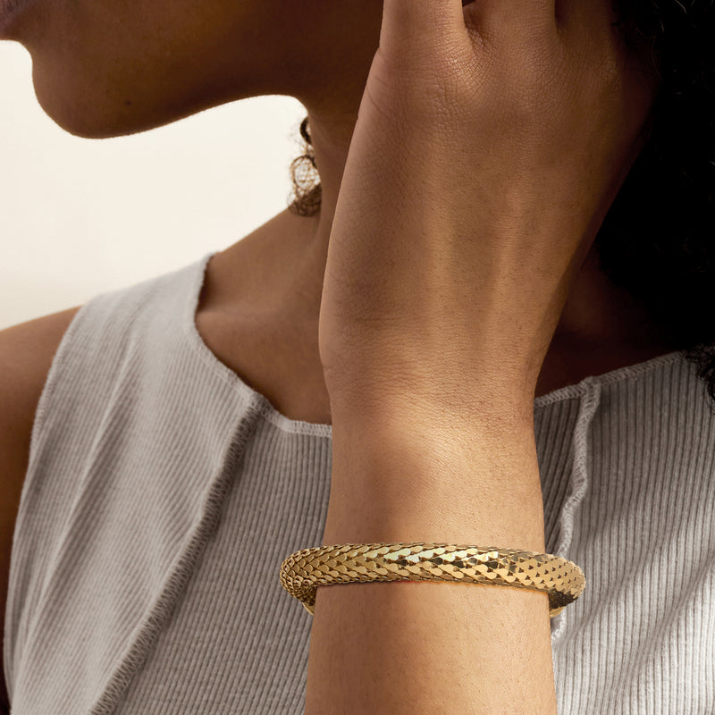 Gold-plated scale-pattern bracelet worn on wrist with small clasp and links visible