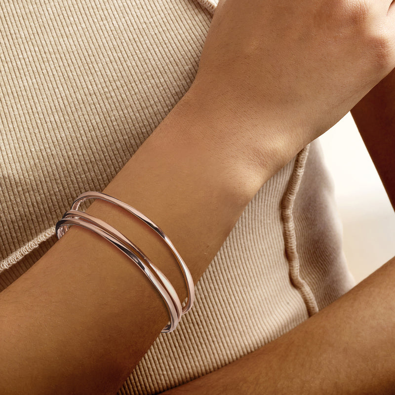 Three rose gold bangles on wrist, slim open cuff bracelets