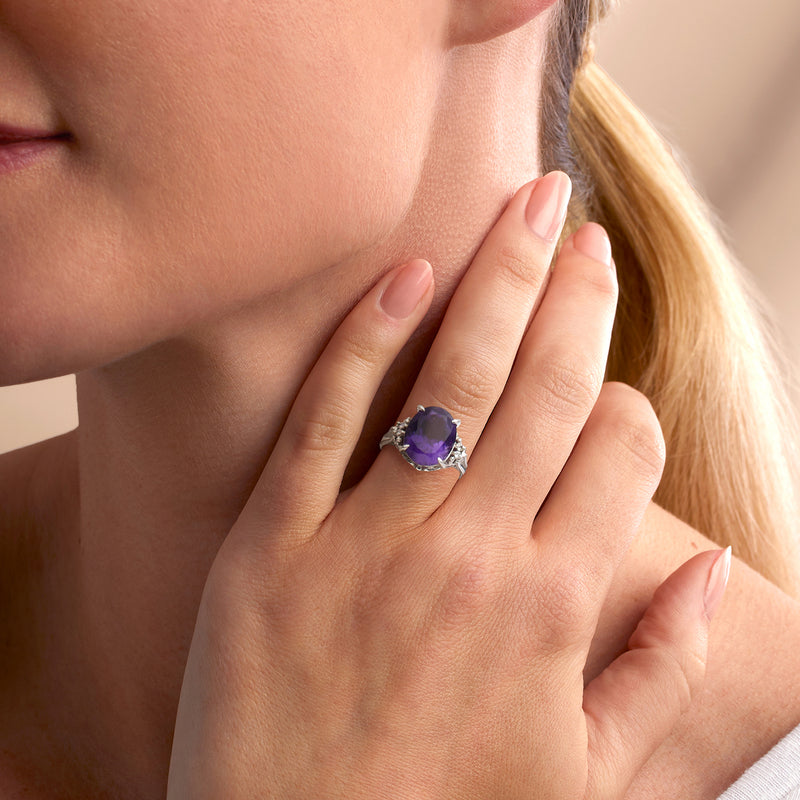Amethyst and diamond platinum ring on hand, oval stone in prong setting