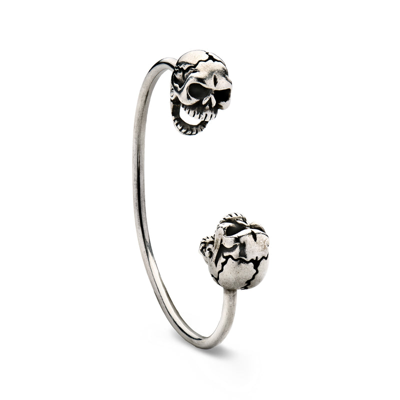 Sterling silver double-skull cuff bracelet, angled view with raised skull face