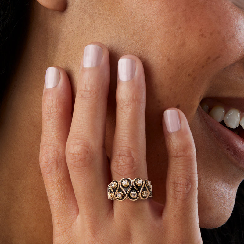 Ruffled black-enamel diamond ring on hand with round stones in 14kt yellow gold