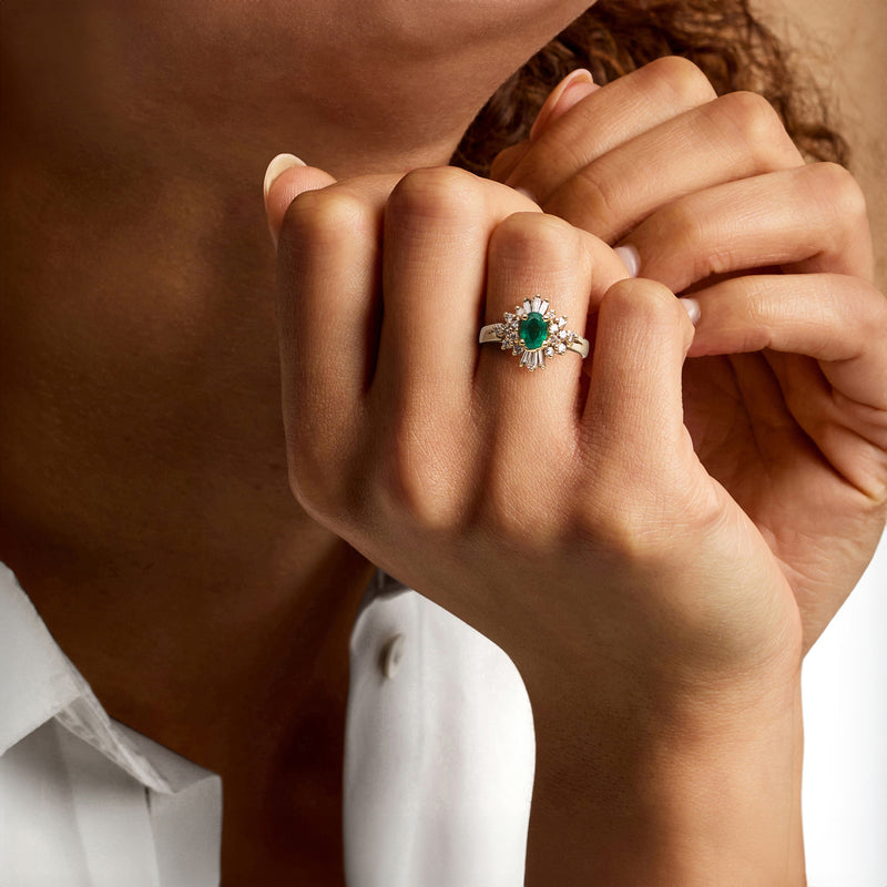 Emerald and diamond ring on finger in 14kt yellow gold setting