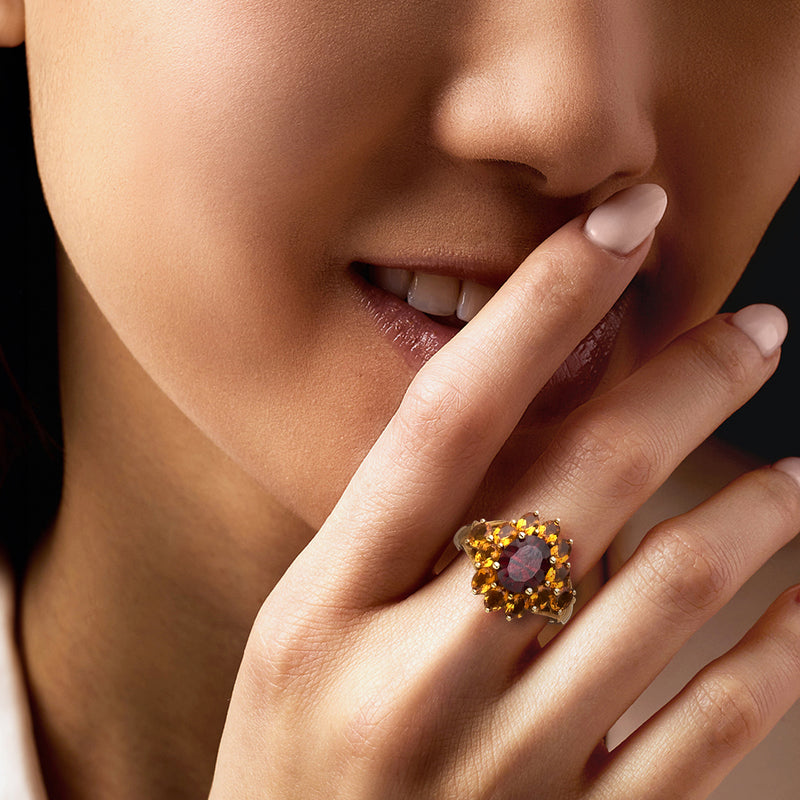 Garnet-style ring in yellow gold with dark red center, worn on finger