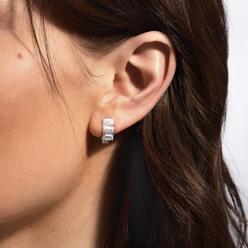 Emerald-cut diamond huggie hoop earring on ear, white gold, close-up