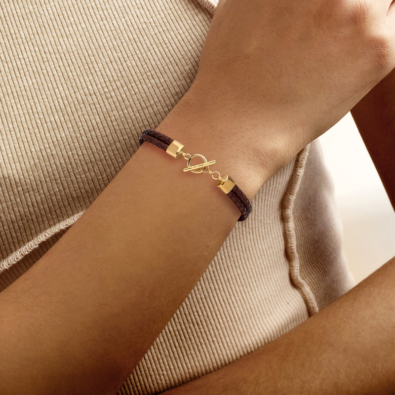 Brown leather braided bracelet on wrist with gold-tone toggle clasp