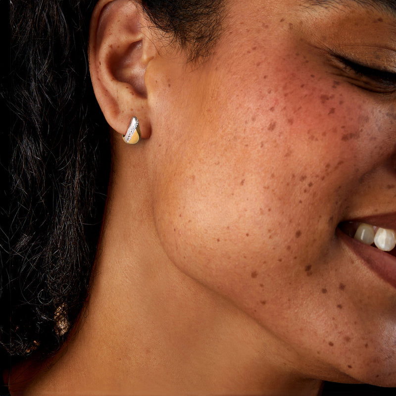 Reversible curved post earrings with white stones on model’s ear