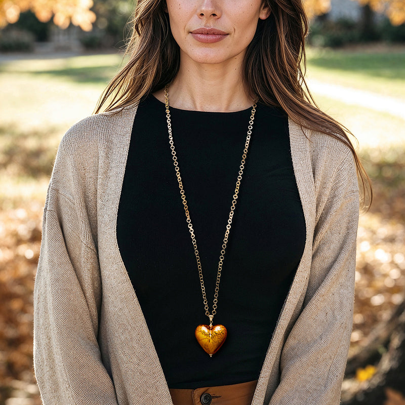 Amber glass heart pendant necklace with yellow gold-plated chain, worn on model