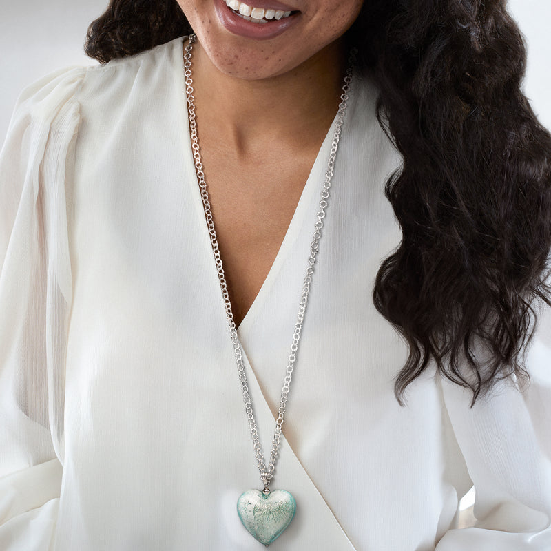 Aqua-blue heart pendant necklace with long silver chain worn with a white blouse