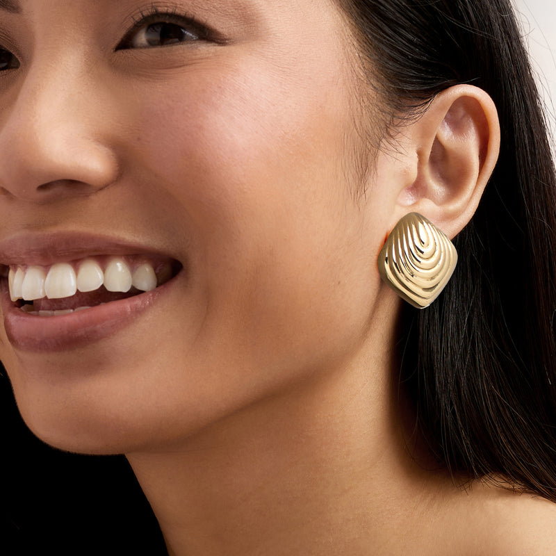Vintage 14kt yellow gold ripple earrings worn on ear, ridged dome close-up
