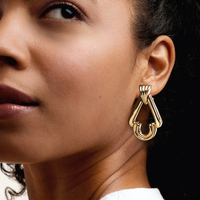 Yellow gold doorknocker earrings worn on ear, clip/post back visible